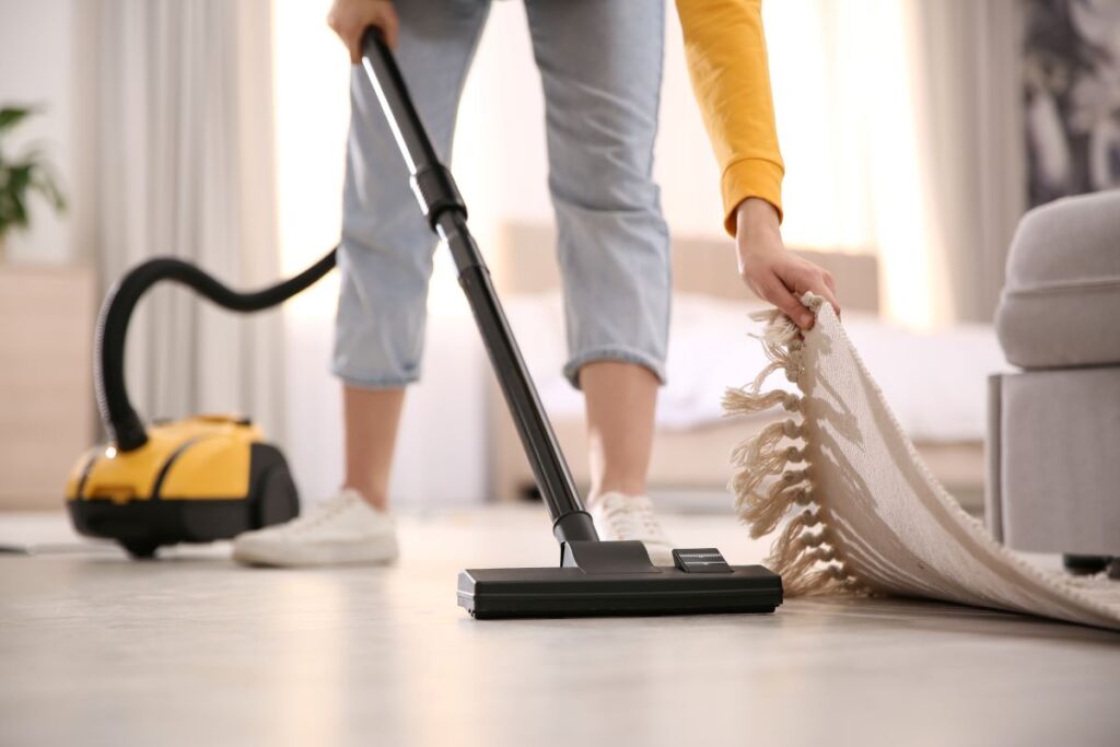 Personne effectuant de l'aide à domicile en passant l'aspirateur sur un tapis.