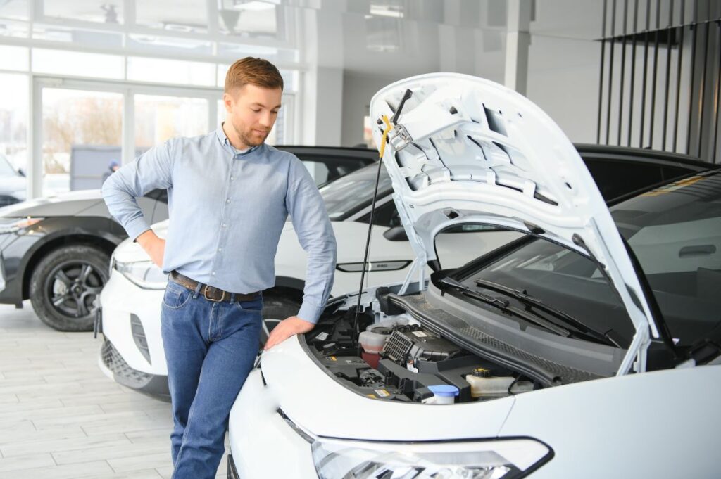 Un homme heureux choisit une nouvelle voiture électrique chez un concessionnaire automobile grâce aux Aides financières pour l'achat de véhicule électrique.