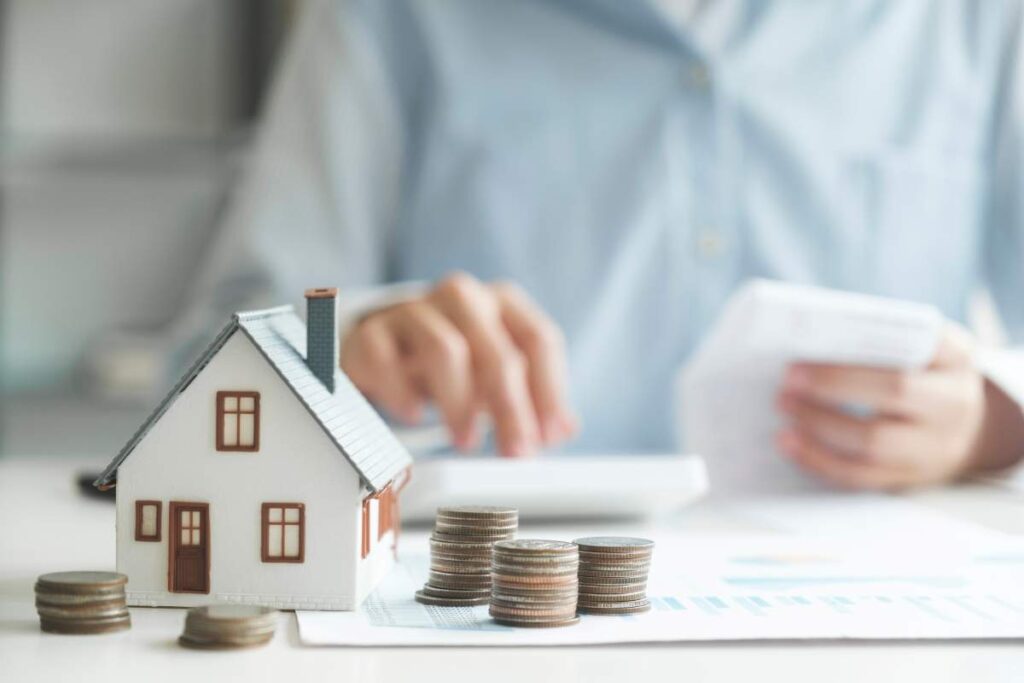 Une maison miniature, des piles de pièces et une personne faisant des calculs illustrent le soutien financier offert par le Programme de supplément au loyer au Québec (PSLQ).