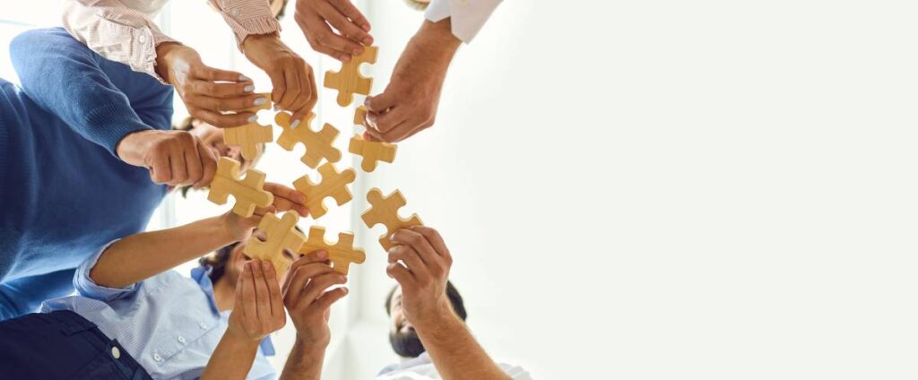Des mains se rejoignent pour assembler des pièces de puzzle, symbolisant la collaboration et l’unité derrière Demarches.quebec, une plateforme dédiée à simplifier les démarches administratives.